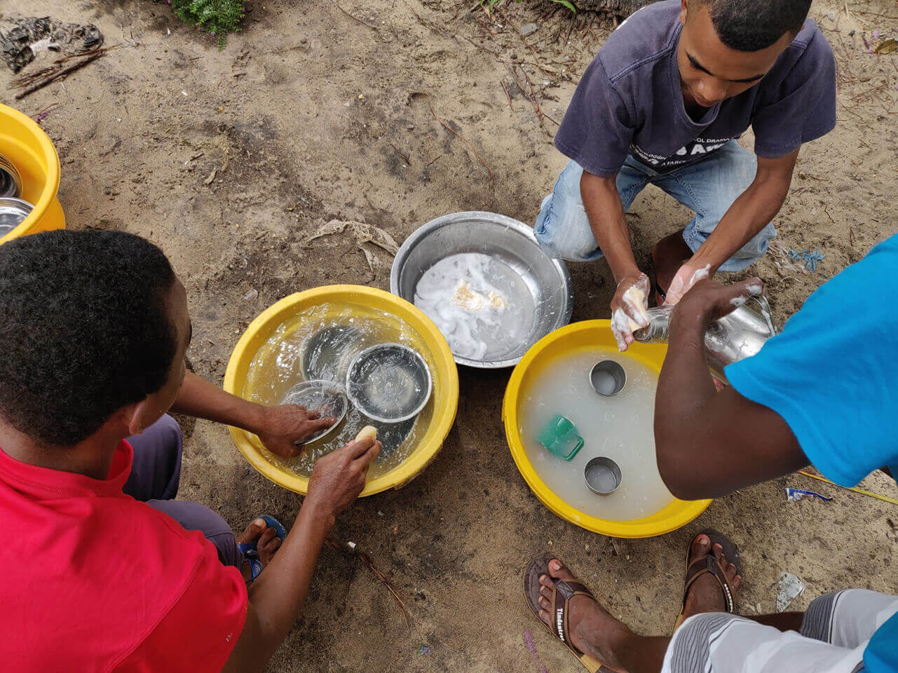 Cleaning up after lunch by washing the dishes in separate buckets